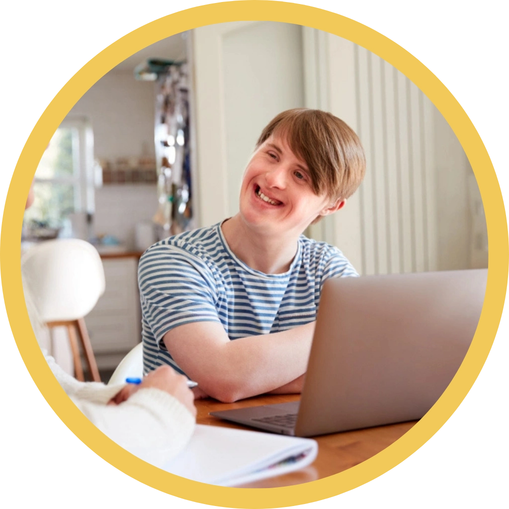 young down syndrome boy smiling and looking at carer
