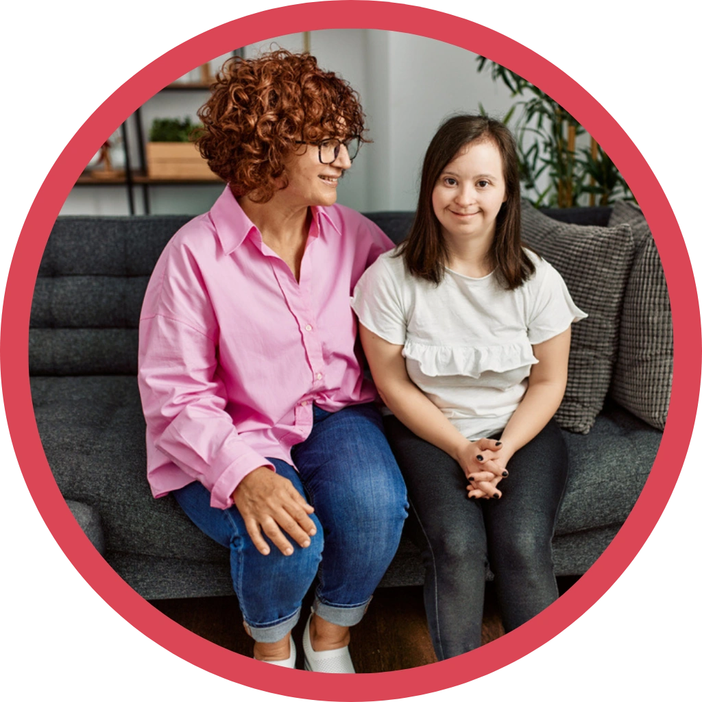 carer with down syndrome girl sitting on sofa