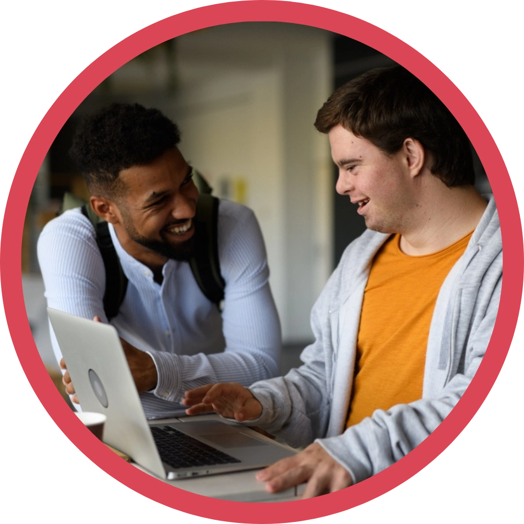 carer helping young down syndrome boy fill a form on laptop