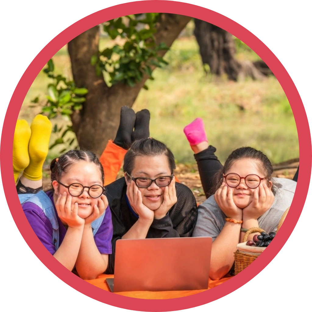 three down syndrome disabled girls watching movie together in a park